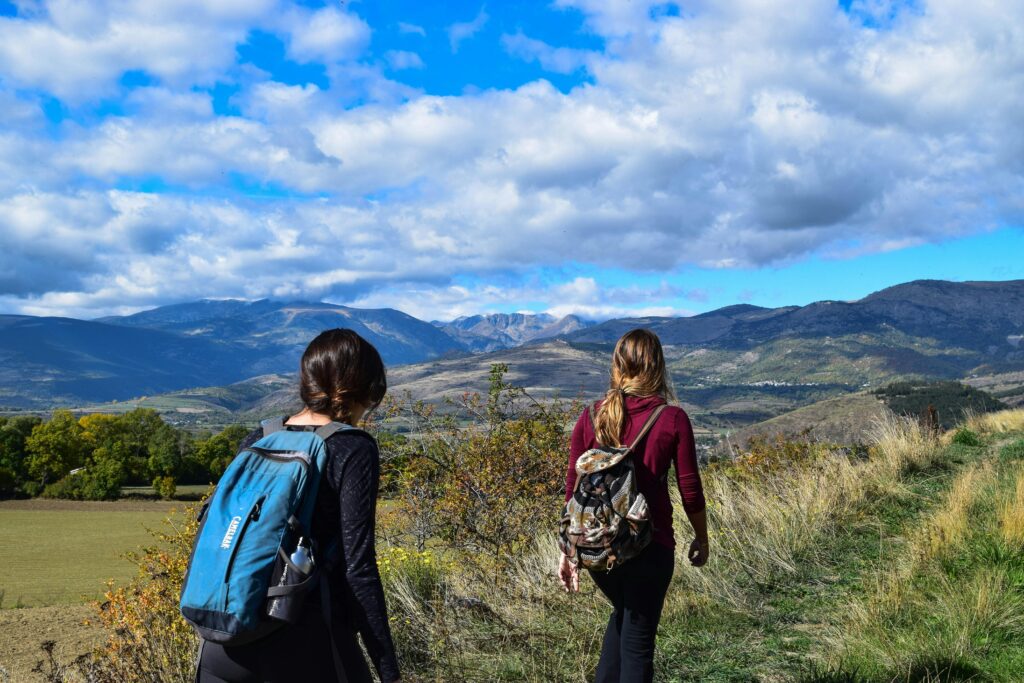 Zwei Frauen die durch eine bergige Landschaft wandern.